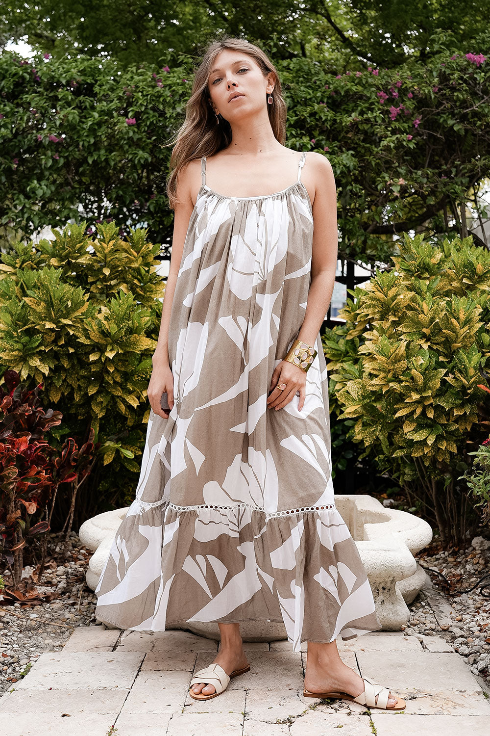 Woman wearing a floral dress standing outdoors with greenery in the background