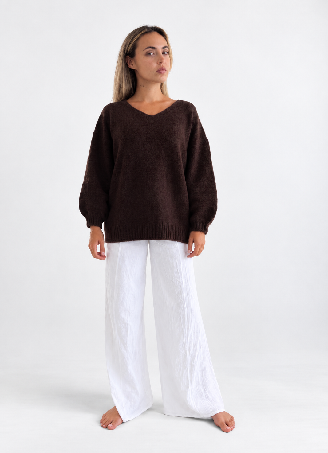 Vail V-Neck Sweater in Chocolate, front studio view with white trousers.