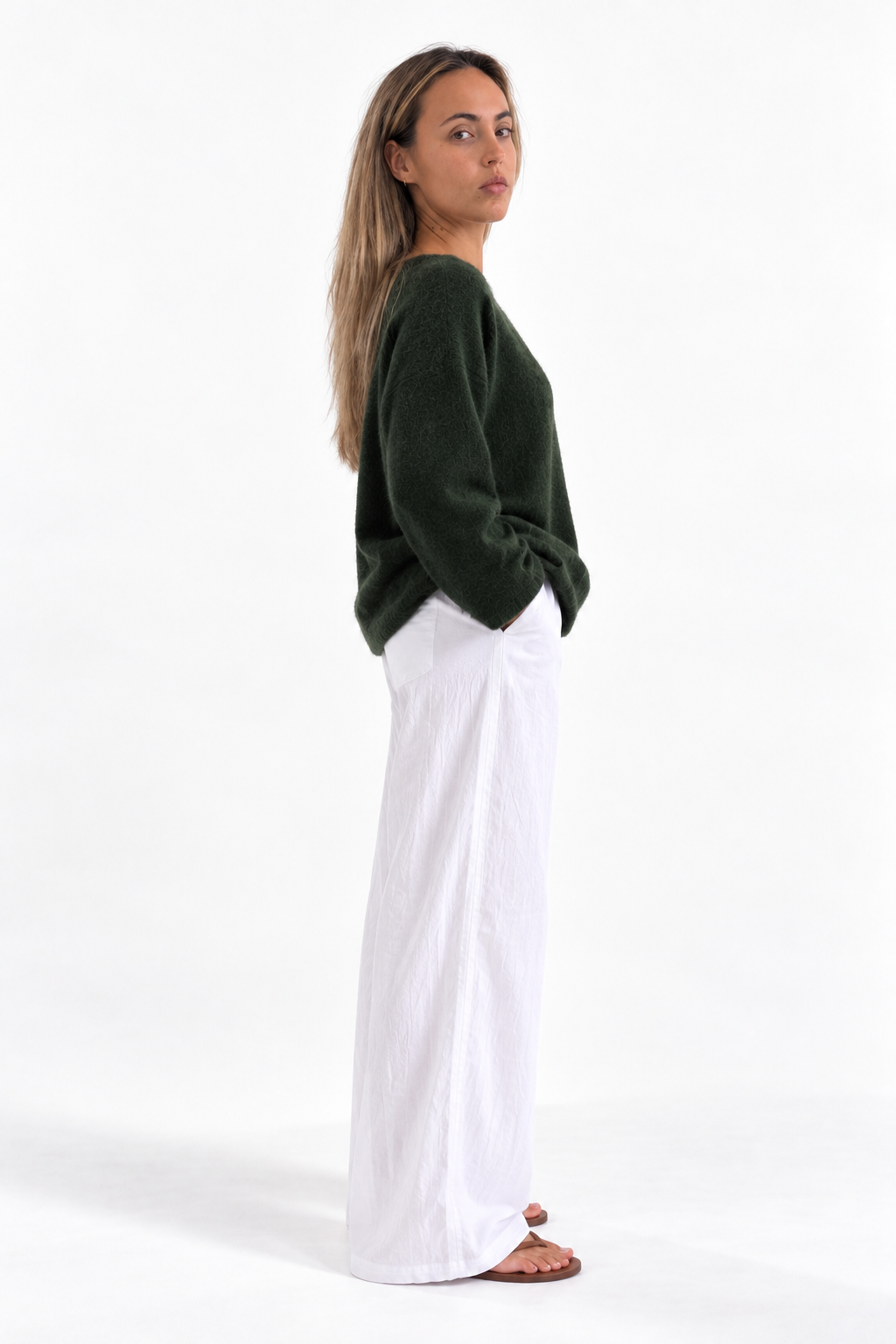 Merry Boatneck Sweater in Army Green, side studio view with white trousers.
