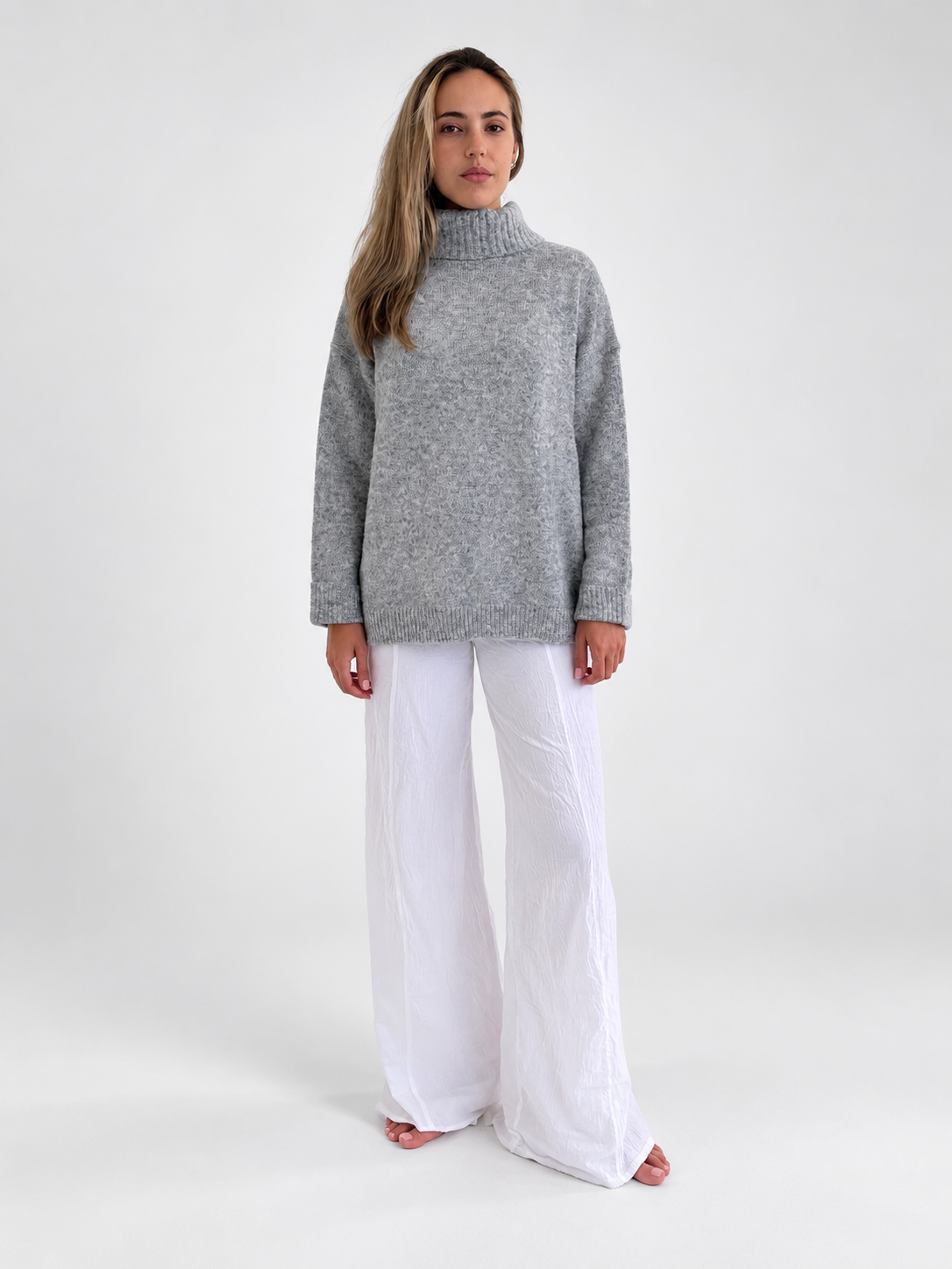 Cozy Turtleneck Sweater in Heather Grey, front studio view with white trousers.