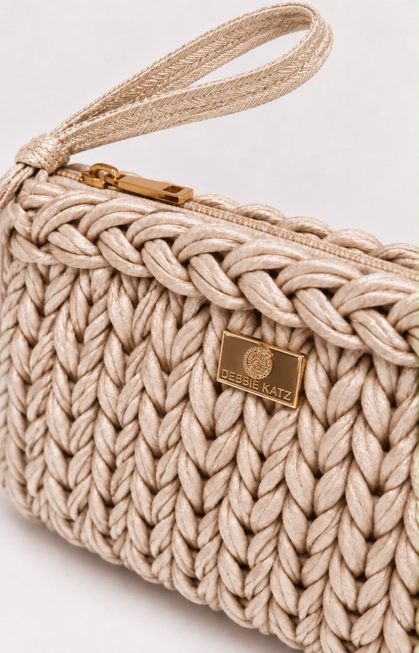 Bardot Light Gold crochet clutch detail showing the flat woven wrist strap, gold-tone zipper and Debbie Katz logo plaque.